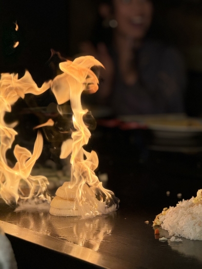 A stack of onions caramelizes amidst a tall tower of flames on a teppanyaki grill top at Shogun Japanese steakhouse.  