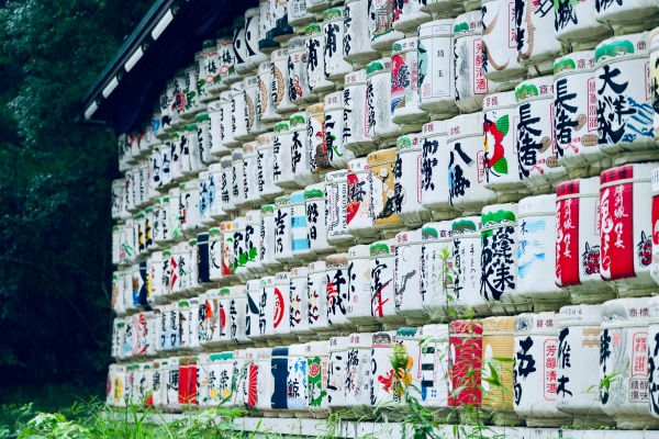 A wall of decorated sake barrels stacked 7 rows high. 